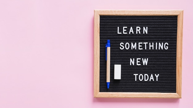Aprende algo nuevo hoy texto en pizarra con lápiz y borrador sobre fondo rosa