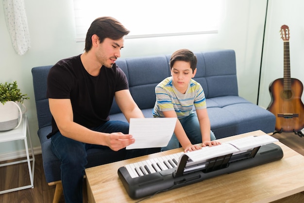 Aprender a tocar una nueva canción en el piano. Joven artístico hablando con su profesor de música durante una lección privada