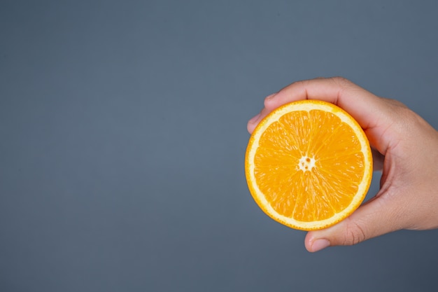 Apretón anaranjado de la mano en fondo gris.