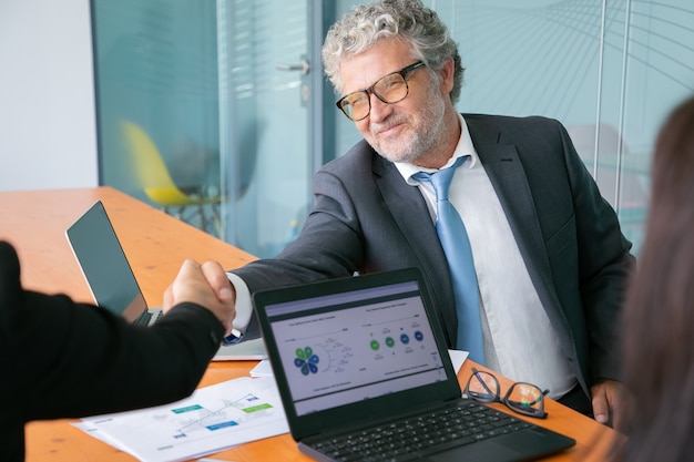 Apretón de manos de empresario caucásico canoso y sonriente