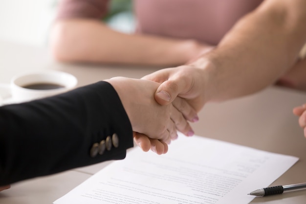 Foto gratuita apretón de manos del hombre y de la mujer después de firmar los documentos, trato acertado, primer