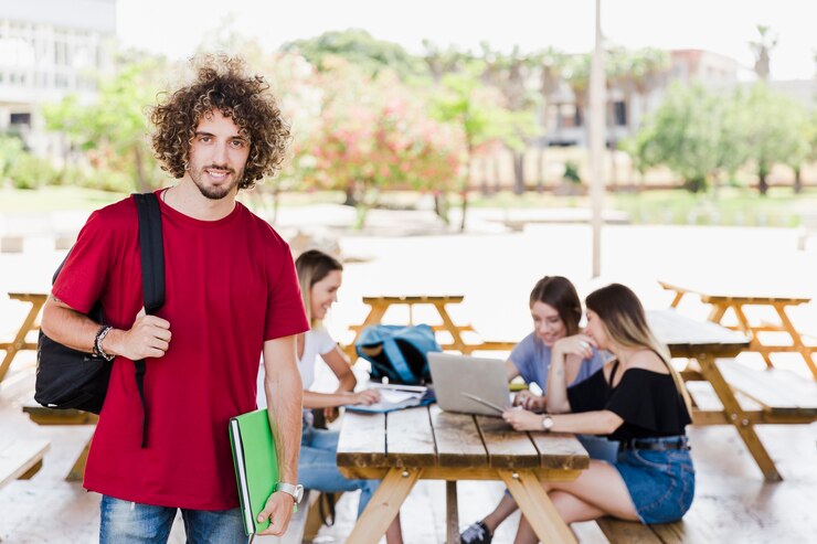 Foto gratuito apuesto estudiante de pie cerca de amigos