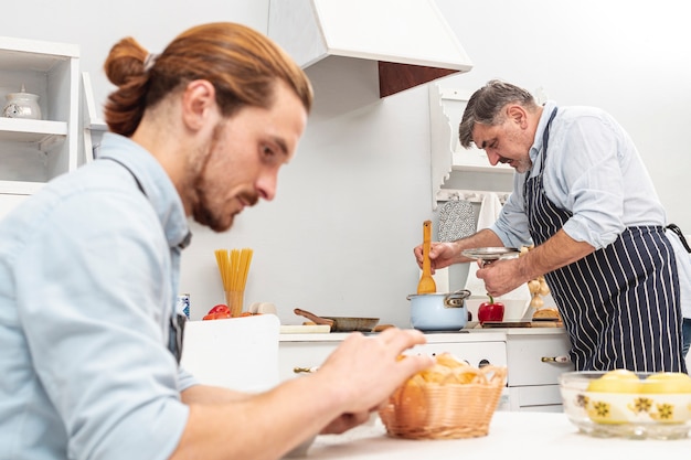 Apuesto hijo y padre cocinando