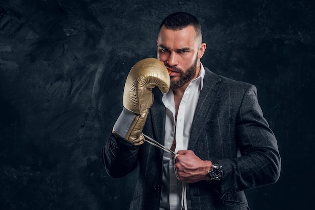 Un apuesto hombre brutal con guantes de boxeo protectores se está cubriendo la boca mientras posa para el fotógrafo.