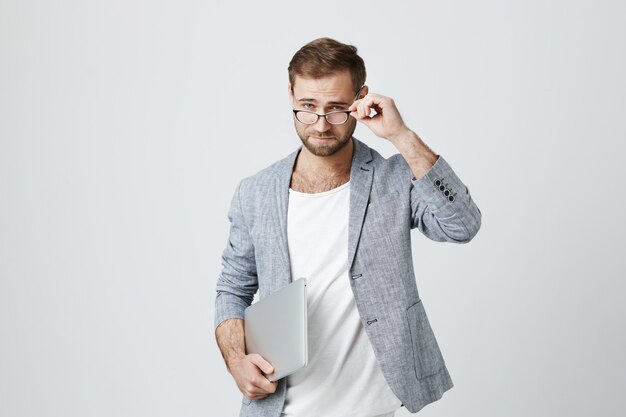 Apuesto hombre emprendedor elegante en vasos con laptop