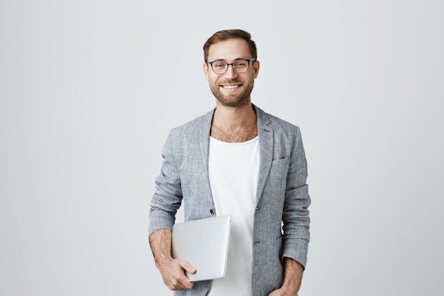 Apuesto hombre emprendedor elegante en vasos con laptop