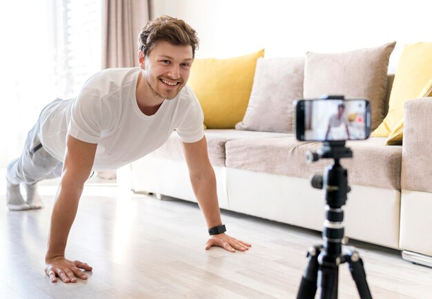 Apuesto hombre grabando entrenamiento personal en casa