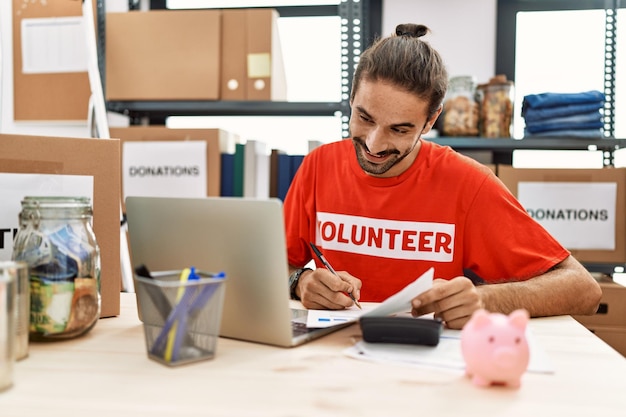 Foto gratuita apuesto hombre hispano trabajando como voluntario haciendo contabilidad en el stand de donación