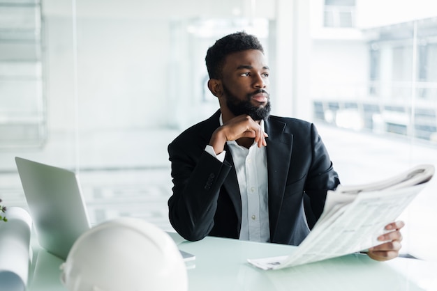 Foto gratuita apuesto hombre de negocios afroamericano con periódico cerca de la oficina del centro de negocios