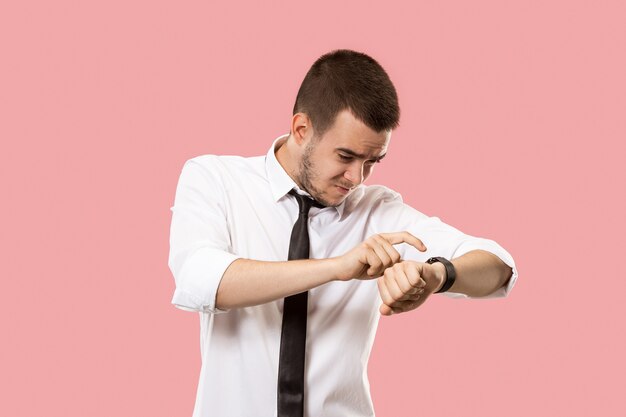 Apuesto hombre de negocios comprobando su reloj de pulsera aislado en rosa.