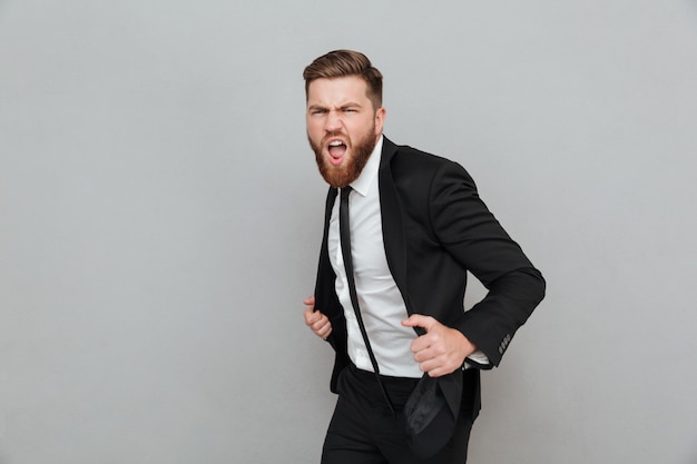 Apuesto hombre de negocios elegante en traje posando mientras está de pie