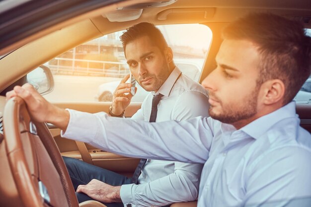 Un apuesto hombre de negocios con estilo y su conductor en un auto.