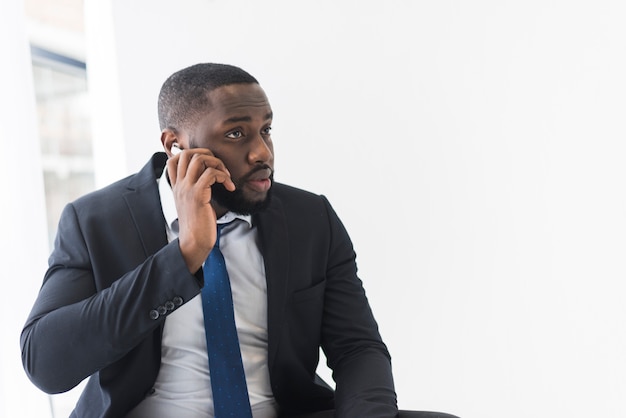 Apuesto hombre de negocios étnicos hablando por teléfono