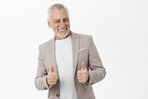 Apuesto hombre de negocios exitoso sonriendo, mostrando el pulgar hacia arriba en señal de aprobación