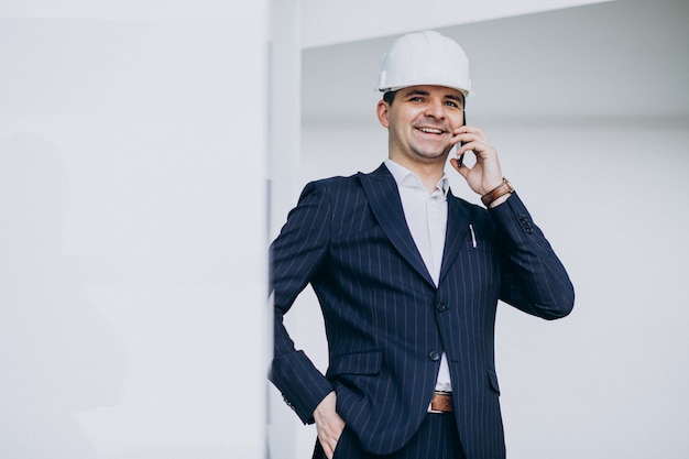 Apuesto hombre de negocios ingeniero en casco en un edificio