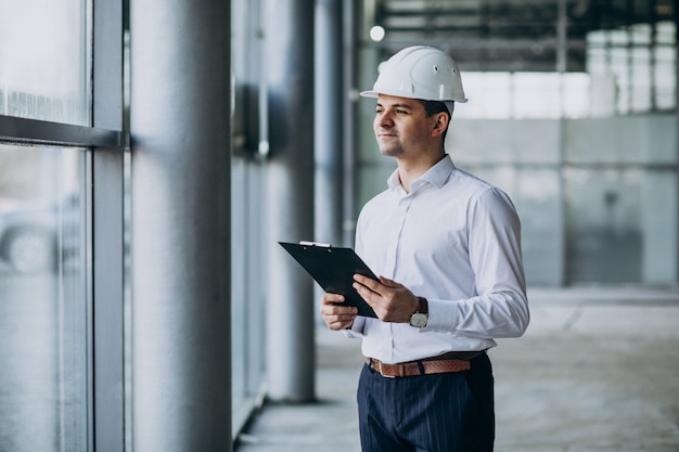 Apuesto hombre de negocios ingeniero en casco en un edificio