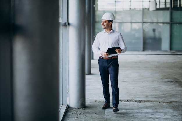 Apuesto hombre de negocios ingeniero en casco en un edificio