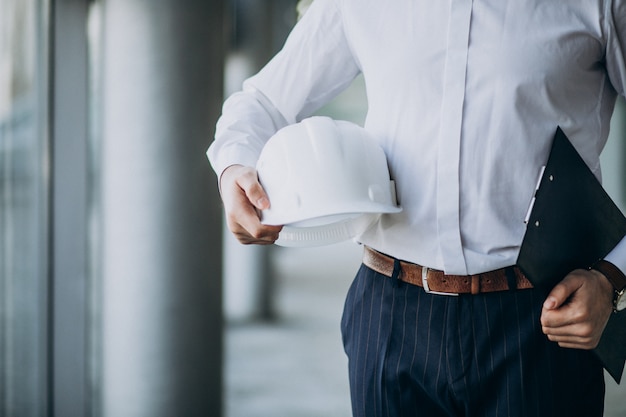 Apuesto hombre de negocios ingeniero en casco en un edificio