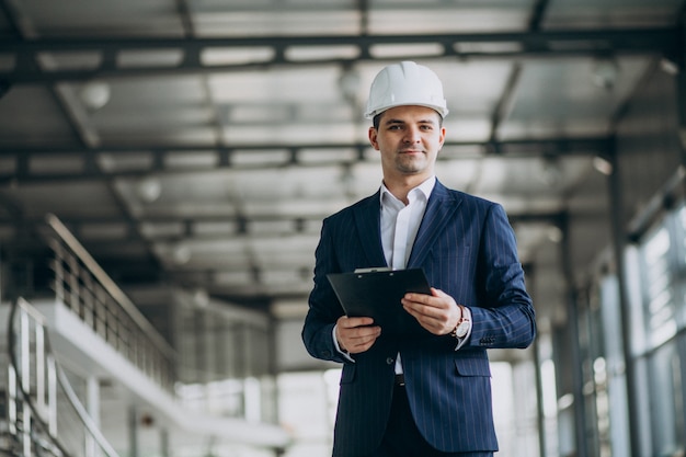 Apuesto hombre de negocios ingeniero en casco en un edificio