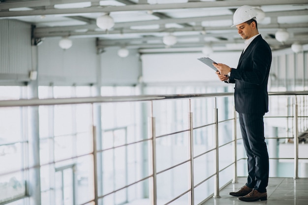 Apuesto hombre de negocios ingeniero en casco en un edificio