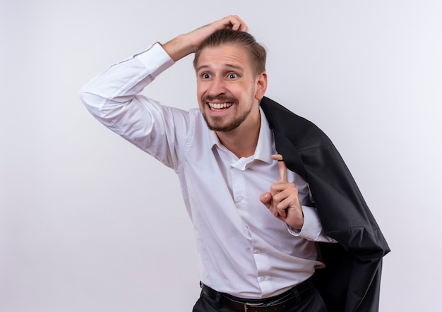 Foto gratuita apuesto hombre de negocios llevando su chaqueta al hombro mirando a un lado confundido y muy ansioso de pie sobre fondo blanco.