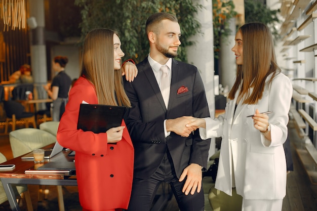 Apuesto hombre de negocios con mujeres de pie y trabajando en un café