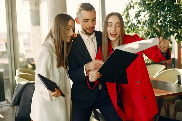 Apuesto hombre de negocios con mujeres de pie y trabajando en un café