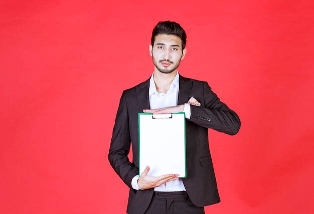 Foto gratuita apuesto hombre de negocios seguro vistiendo traje y sosteniendo el bloc de notas