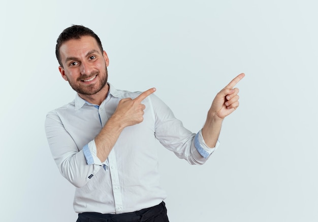 Foto gratuita apuesto hombre sonriente apunta al lado con las dos manos aisladas en la pared blanca