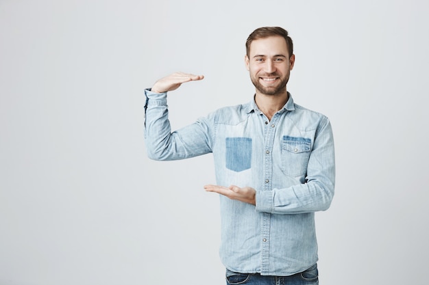 Apuesto hombre sonriente mostrando el tamaño de algo grande