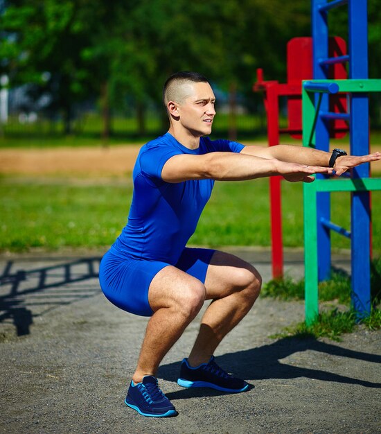 Apuesto hombre srtong saludable hombre masculino haciendo ejercicio en el parque de la ciudad - conceptos de fitness en un hermoso día de verano cerca de la barra horizontal