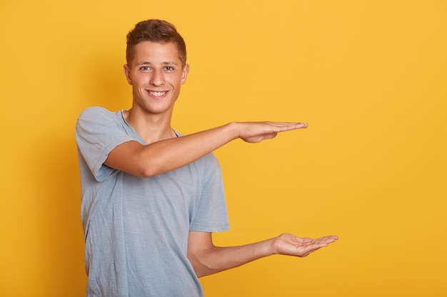 Apuesto joven alegre haciendo gesto, mostrando medida