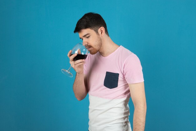 Apuesto joven bebiendo vino en un azul.