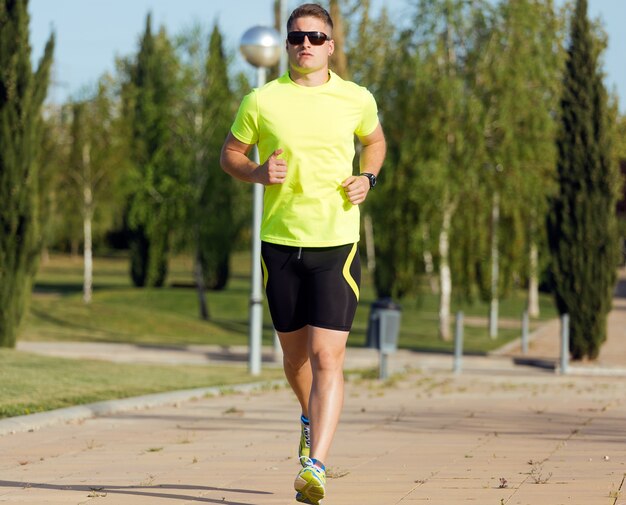 Apuesto joven corriendo en el parque.