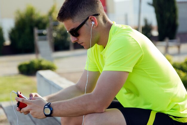 Apuesto joven escuchar música después de correr.