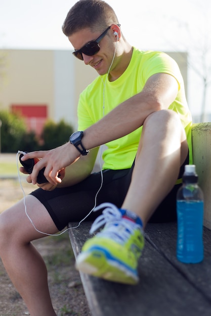 Apuesto joven escuchar música después de correr.