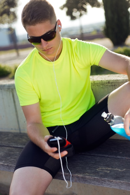 Apuesto joven escuchar música después de correr.