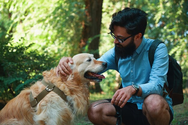 Apuesto joven con golden retriver al aire libre