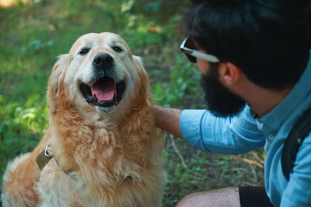 Apuesto joven con golden retriver al aire libre