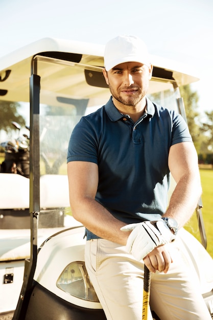 Apuesto joven golfista masculino con club de descanso