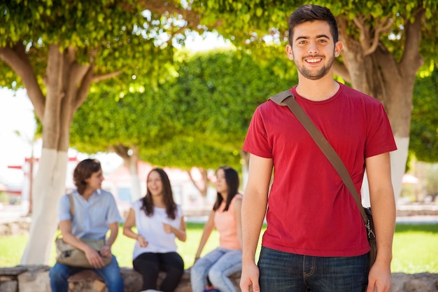 Apuesto joven hispano con una mochila escolar colgando en la universidad