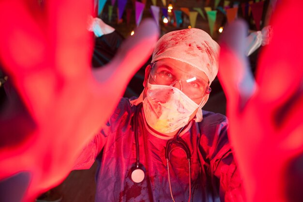 Apuesto joven médico en una fiesta de halloween con una expresión espeluznante. Celebración de Halloween en un club nocturno.