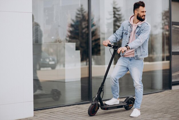 Apuesto joven montando scooter eléctrico