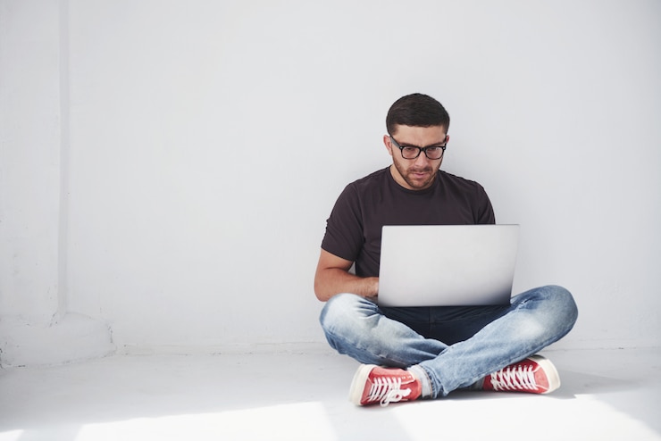 Foto gratuito apuesto joven con portátil y comprobar su horario en blanco