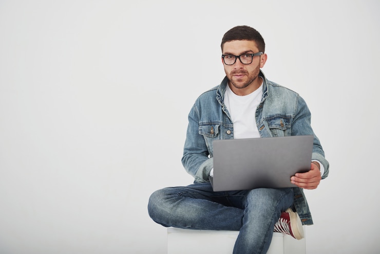 Foto gratuito apuesto joven con portátil y comprobar su horario en blanco