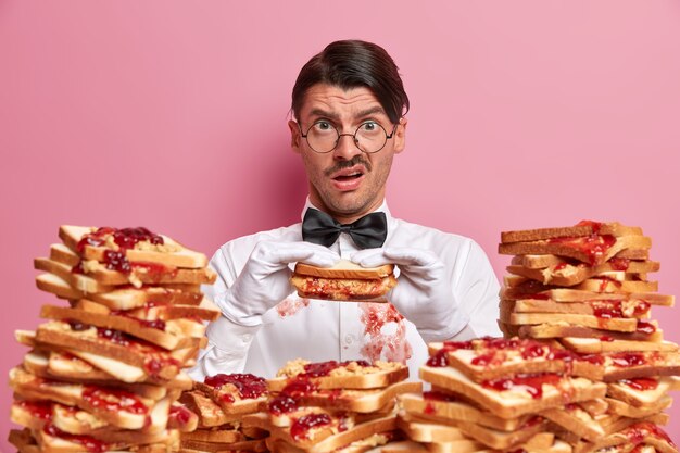 Apuesto joven rodeado de sándwiches de gelatina de mantequilla de maní