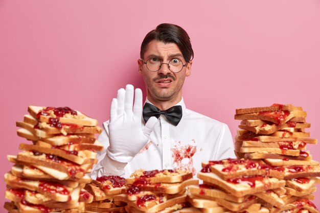 Apuesto joven rodeado de sándwiches de gelatina de mantequilla de maní