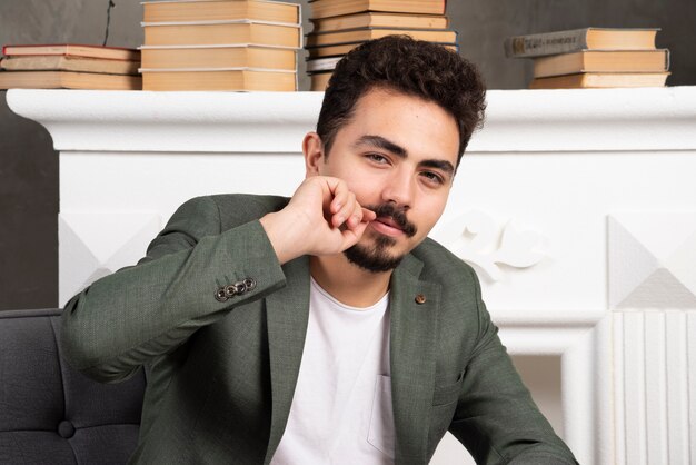 Apuesto joven sonriente sosteniendo su mano a su bigote.