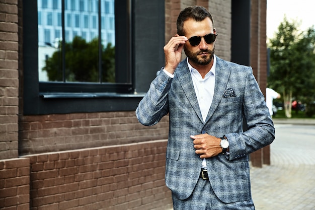 Apuesto modelo de empresario de moda vestido con elegante traje a cuadros posando en la calle