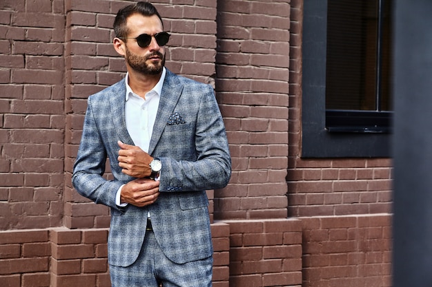 Apuesto modelo de empresario de moda vestido con elegante traje a cuadros posando en la calle